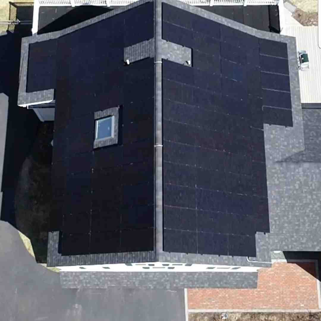 Aerial view of a house roof covered with black solar panels and a single skylight near the center.