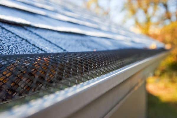 Close-up of a house’s roof with a mesh gutter guard installed—expert Gutter Installations keep leaves and debris out of your gutters.